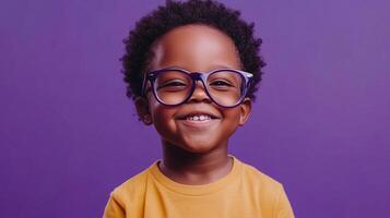 Happy young child wearing glasses smiles brightly against a solid background. He is wearing a yellow shirt and appears optimistic. photo