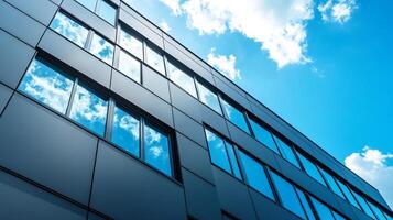 Modern facade reflects sky and clouds on a building with multiple windows. Building represents modern architecture with a clean design. photo