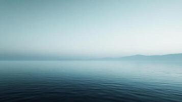 Calm ocean surface at the horizon, minimalist landscape with serene water reflecting the soft light, mountains faintly in the distance. photo