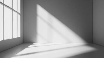 Sunlight streams into a stark, white corner room through a large window, creating contrasting patterns of light and shadow on the walls. photo