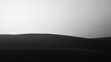 Monochromatic landscape of dark undulating hills against a bright sky, creating a stark contrast and a sense of peaceful isolation. photo