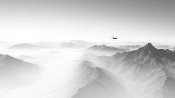 Airplane soars over the misty mountains, a monochromatic journey through the skies, blending into the foggy landscape, peak silhouettes photo