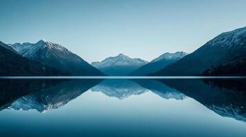 Mountains reflected in the water's serene surface creates a mirror image, enhancing its scenic landscape against a serene backdrop. photo