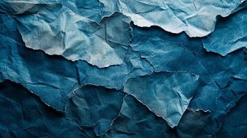Torn and crumpled blue paper texture featuring rough edges and deep shadows, creating an abstract pattern perfect for artistic backgrounds. photo