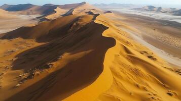 Sweeping sand dunes present a stark, beautiful desert landscape with wavy patterns etched into the dunes. The desert is dry and expansive. photo