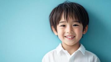 Portrait of a smiling young boy with dark hair against a bright blue background in a studio setting. The child looks directly at the camera. photo
