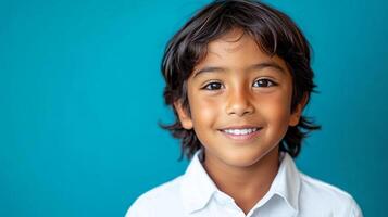 A charming boy with dark hair smiles brightly against a vibrant turquoise background, showcasing his innocent joy and youthful exuberance. photo