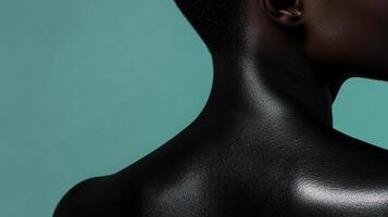 Close-up shot capturing the graceful curve of a person's neck and shoulder against a vibrant turquoise background, creating a striking contrast. photo