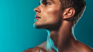 Portrait of a handsome man in profile looking upward, lit with blue light, showcasing strong features and a youthful complexion. photo
