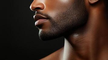 Striking profile portrait of a handsome person, featuring a neat dark beard, and warm lighting against a dark background. photo