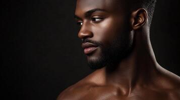 Striking portrait of a handsome man with deep skin. The lighting highlights his features against the stark black background. photo