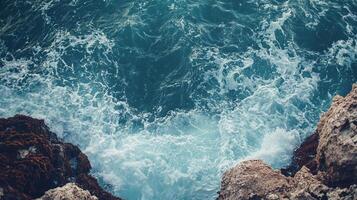 Ocean waves crashing against rocky shore, captured from above. Turquoise water and natural rock formations in coastal scenic beauty. photo