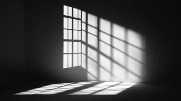 A monochrome image showcasing natural light streaming through a grid window, casting striking shadows across the walls and floor of a room. photo