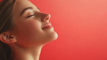 A portrait of a young woman in profile against a vibrant red backdrop, eyes gently closed, conveying a sense of serenity and peacefulness. photo