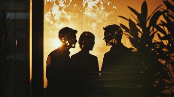 Three people silhouetted against a bright, warm window, creating an atmosphere of mystery and professional connection. photo