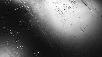 Abstract close-up of a shiny, dark surface with water droplets and scratches, creating a dynamic and textured appearance. photo