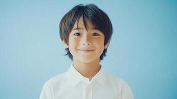 Portrait of a smiling young boy in a white shirt against a pastel blue background, capturing innocence and youthful charm in simple studio setting. photo