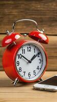 Red Alarm Clock and Smartphone on Rustic Wood photo