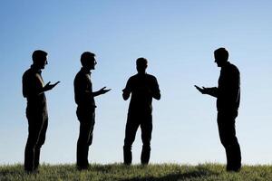 Silhouette of Four People Standing on a Hilltop Against a Blue Sky, Showcasing Teamwork and Communication, Ideal for Business Concepts and Collaboration Visuals, Representing Unity and Agreement photo