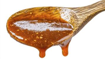 Captivating close-up shot showcasing a wooden spoon generously filled with a luscious, amber-hued caramel sauce, its rich texture and irresistible sweetness practically dripping off the edge, a photo