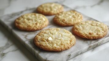 Indulge in the delightful taste of freshly baked white chocolate macadamia nut cookies, perfectly arranged on a sleek marble surface These golden-brown, homemade treats offer a symphony of sweet and photo