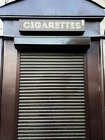 Closed rolling shutter kiosk with cigarettes sign on top viewed closely. photo