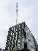 Modern high-rise building under construction with metallic framework against cloudy sky photo