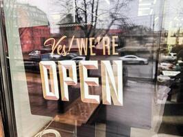 Open sign on a shop window with reflections of a street behind photo