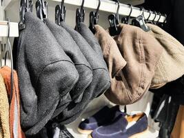 A collection of stylish hats displayed on hooks with shoes nearby photo