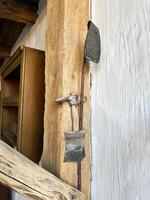 Rustic hand tools displayed on rough wooden supports in a historical setting photo