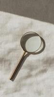 magnifying glass rests on textured beige background, showcasing its elegant design and reflective surface photo