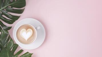 cup of latte coffee with heart shaped milk foam on pink background, surrounded by green leaves, creates warm and inviting atmosphere photo