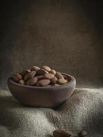 a wooden bowl filled with almonds on burlap background creates rustic and inviting atmosphere photo
