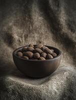 a wooden bowl filled with almonds on burlap background photo