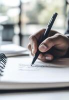 hand writing in open notebook with black pen, capturing thoughts and ideas photo