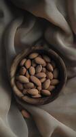 a wooden bowl filled with almonds on textured fabric background, creating warm and inviting atmosphere photo
