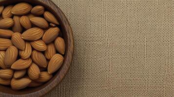 Fresh almonds in wooden bowl on textured jute background create warm, inviting scene photo