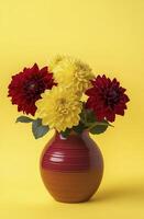 ceramic vase holds vibrant dark red and yellow dahlia flowers against bright yellow background, creating cheerful and lively atmosphere photo