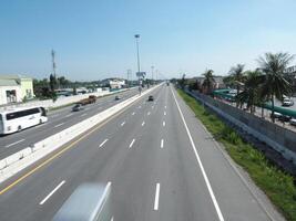 clear highway scene with vehicles and palm trees under blue sky photo