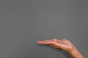 A man's hand with pose or gesture of giving, holding or offering something on gray background photo