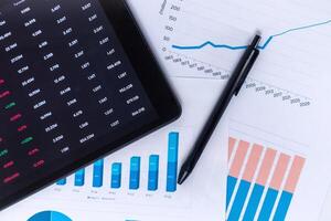 Stock market financial data analysis concept. Investment financial data on digital screen and business data graphs on paper printouts. photo