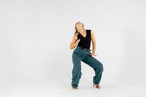 Young blonde dancer posing with hands joined and legs apart on white background. photo