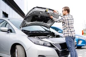 Man checking under the hood of his car to figure out what the problem is photo