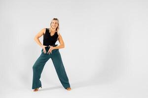 Blonde dancer posing with hands joined and legs apart on white background photo