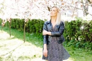 Blonde model posing under blooming tree in spring photo