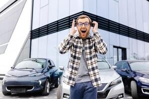 A young man is very impressive and happy, standing in front of his new car. photo