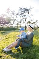 Pregnant mother and her little son walking and hugging in the forest and funny spending time together photo