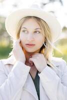 Portrait of pretty blond woman in white hat posing in forest. White summer clothes. photo