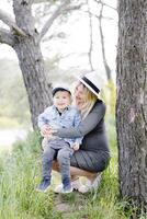 Pregnant mother and her little son walking and hugging in the forest and funny spending time together. photo