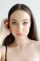 Young woman touching her hair wearing a necklace with a cross pendant. photo
